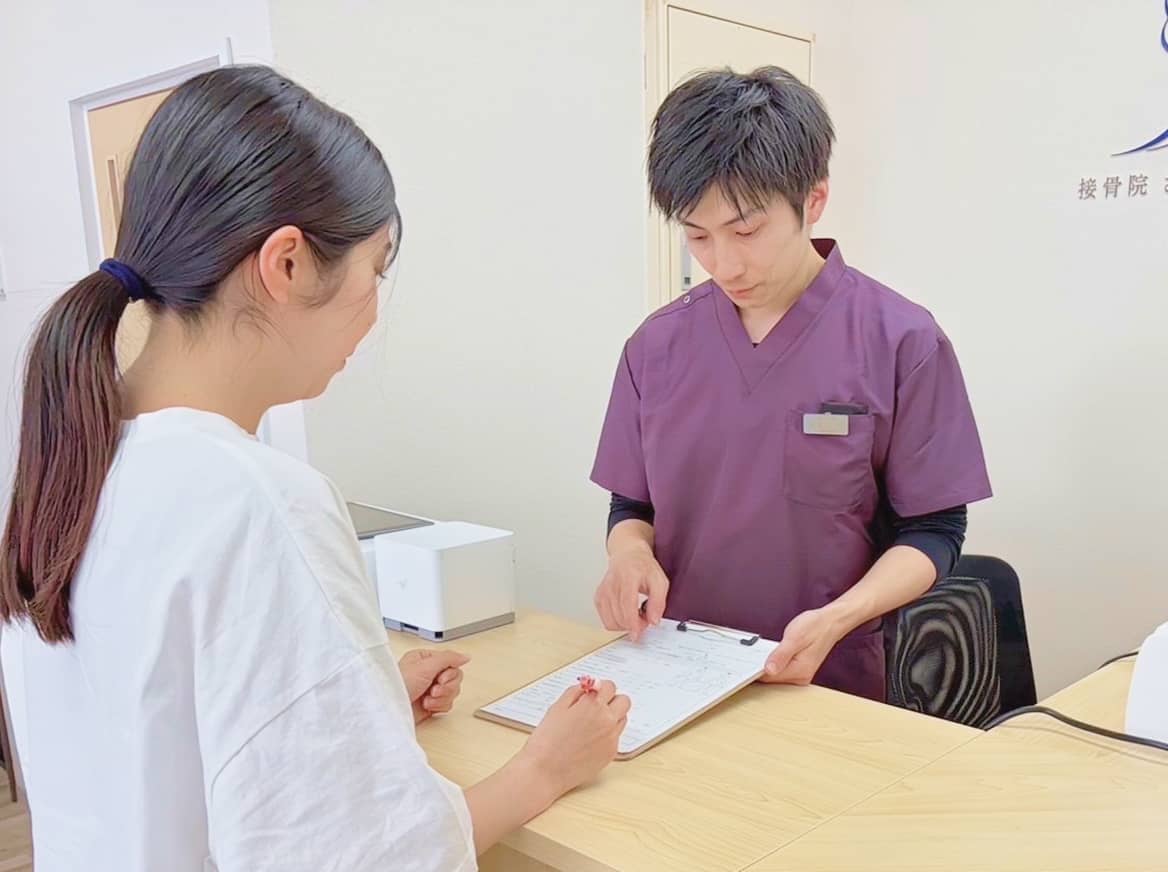 受付でスタッフが患者を対応している様子